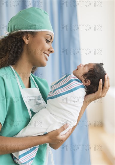 Hispanic doctor holding newborn in hospital