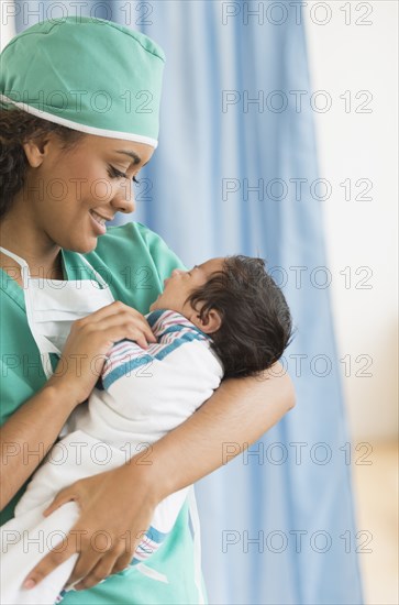 Hispanic doctor holding newborn in hospital