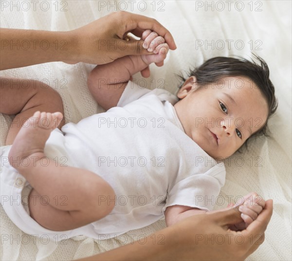 Hispanic mother playing with infant on bed