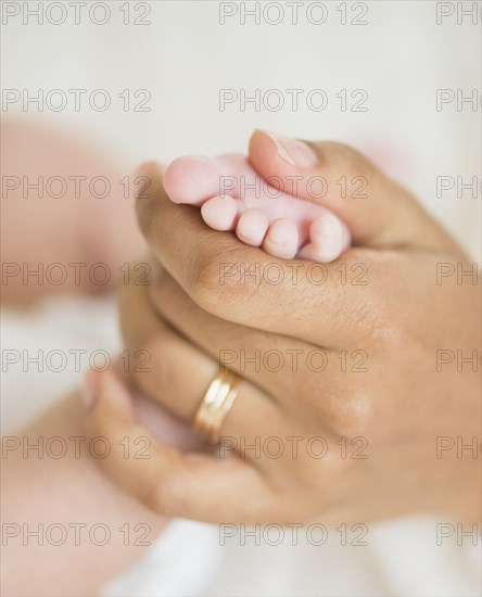 Hispanic mother holding infant's foot