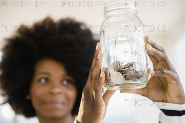 Mixed race woman holding jar of change