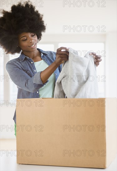 Mixed race woman placing sweater in cardboard box