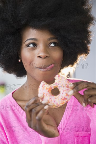 Mixed race woman eating donut