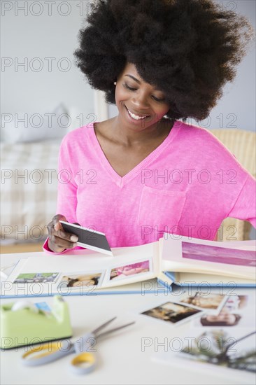 Mixed race woman putting photos in album