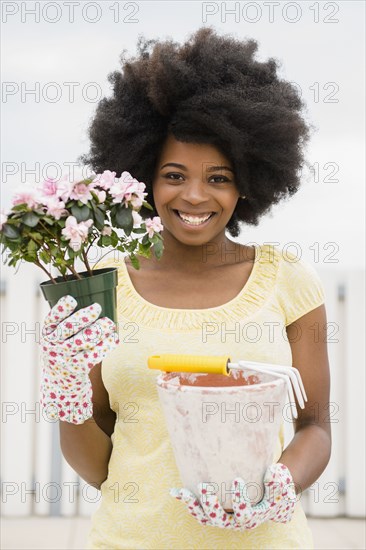 Mixed race woman holding flower and flowerpot