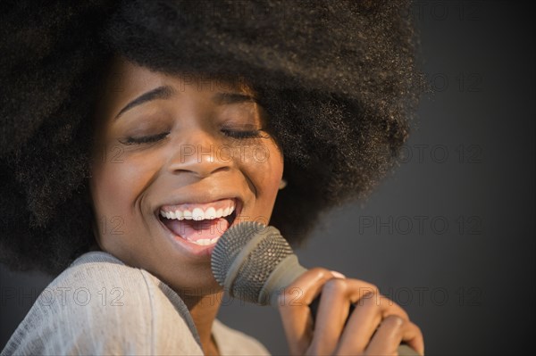 Mixed race woman singing into microphone