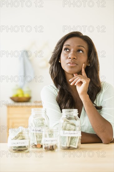 Black woman putting money into savings jars