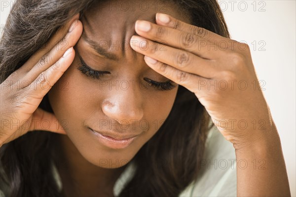 Black woman frowning with head in hands