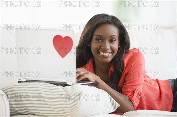 Black woman using laptop on sofa