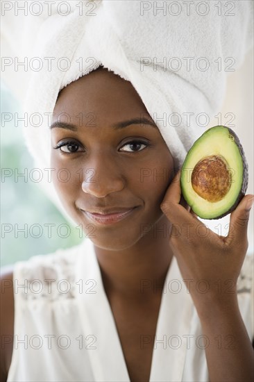 Black woman holding sliced avocado