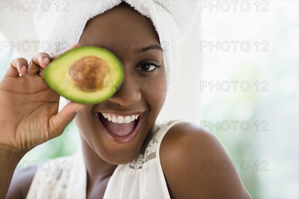 Black woman holding sliced avocado