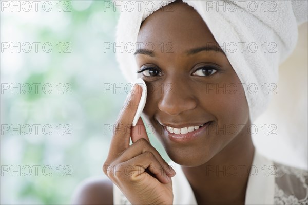 Black woman wiping face with cotton pad