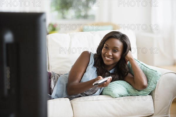 Black woman watching television on sofa