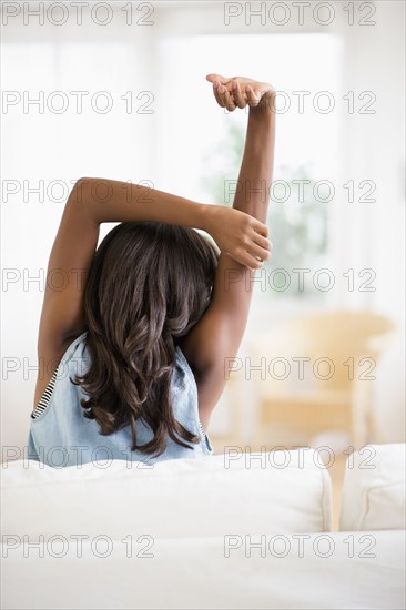 Black woman stretching on sofa