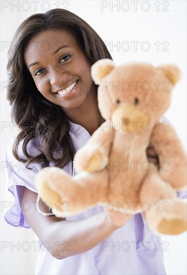 Black nurse holding teddy bear