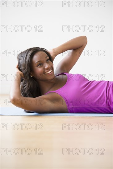 Black woman doing sit-ups on yoga mat