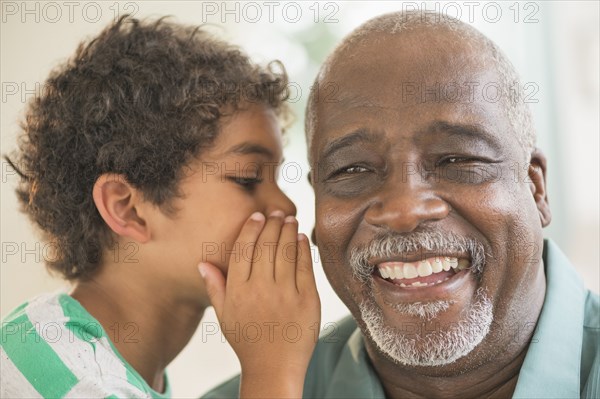 Boy whispering in grandfather's ear