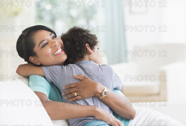 Mother hugging son on sofa