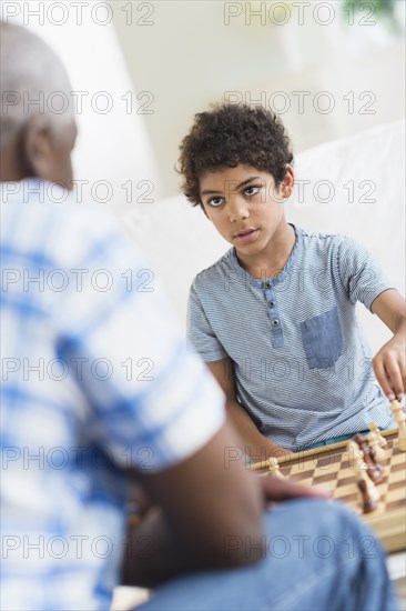 Boy playing chess with grandfather