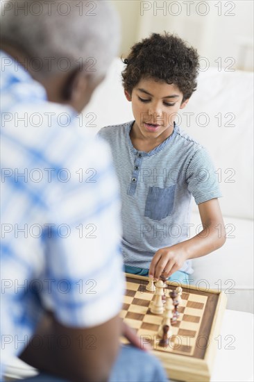 Boy playing chess with grandfather