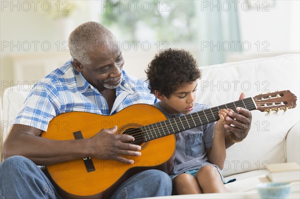 Boy playing guitar with grandfather