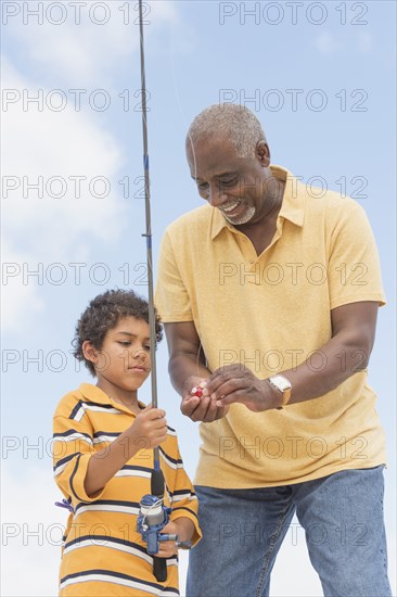 Older man teaching grandson to fish