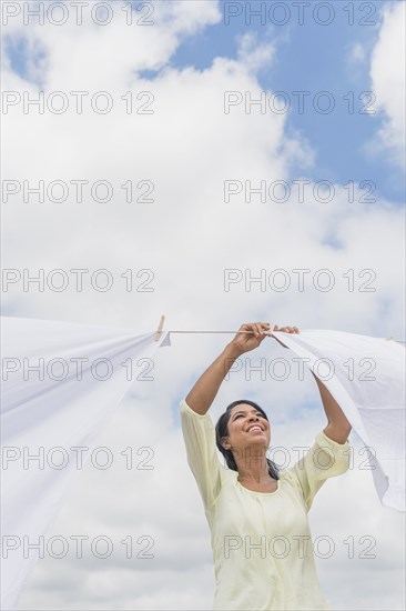 Black woman hanging sheets from clothesline