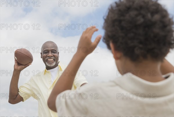 Boy playing catch with grandfather outdoors