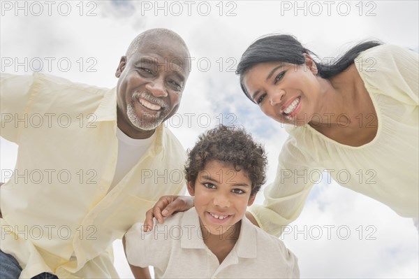 Three generations of family smiling in huddle outdoors