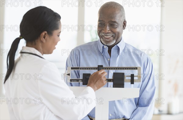 Black doctor weighing patient