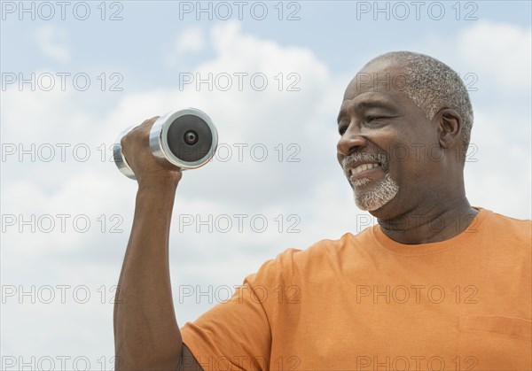 Black man lifting weights outdoors