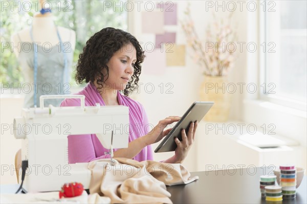 Mixed race dressmaker using digital tablet