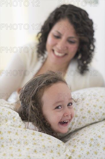 Mixed race mother putting daughter to bed