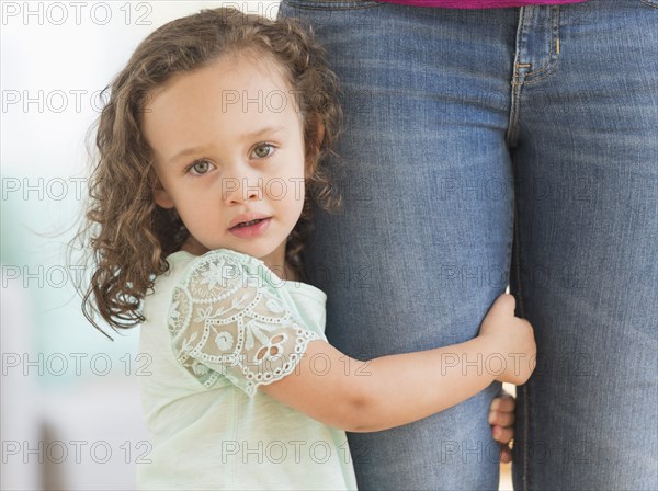 Mixed race girl clinging to mother's leg