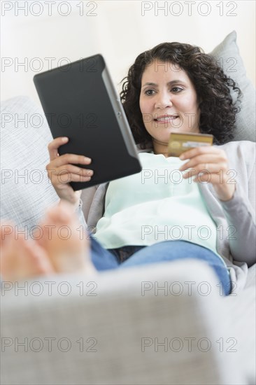 Hispanic woman using digital tablet on sofa