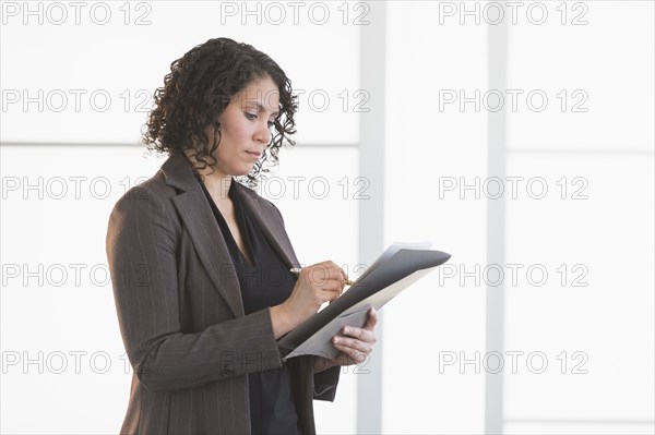 Hispanic businesswoman writing in office