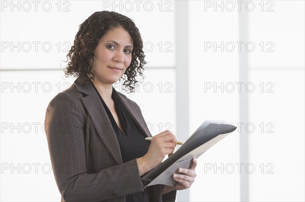 Hispanic businesswoman writing in office