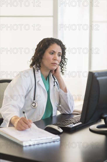 Hispanic doctor working in office