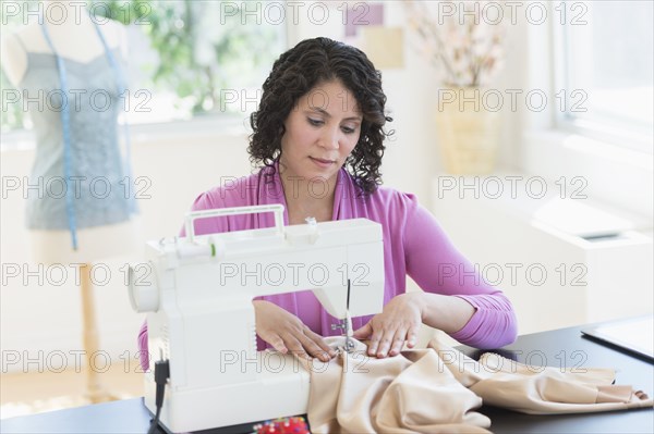 Hispanic dressmaker working at sewing machine