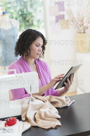 Hispanic dressmaker using digital tablet