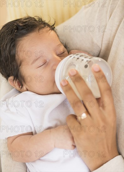 Hispanic mother feeding newborn baby