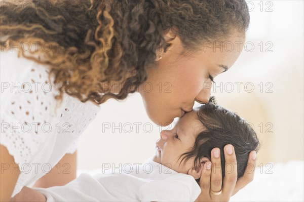 Hispanic mother kissing baby's forehead