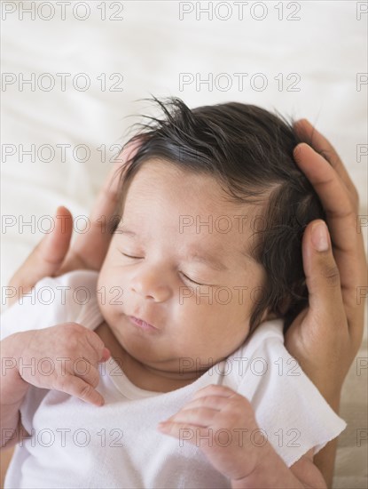 Hispanic mother cradling baby