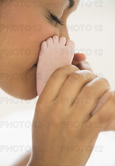 Hispanic mother kissing baby's feet