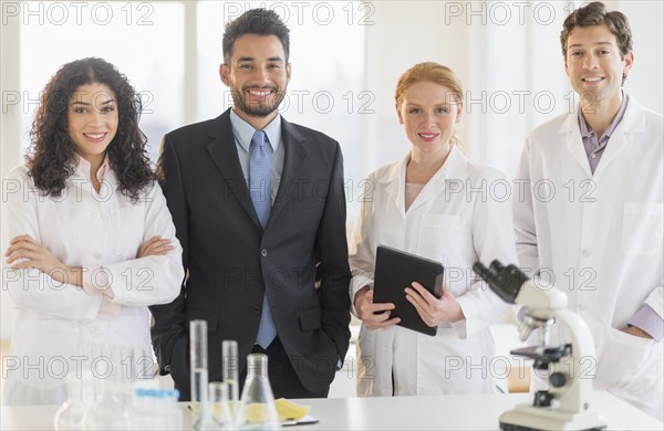 Scientists and businessman smiling in laboratory
