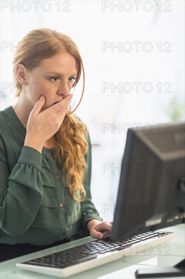 Businesswoman gasping at computer in office