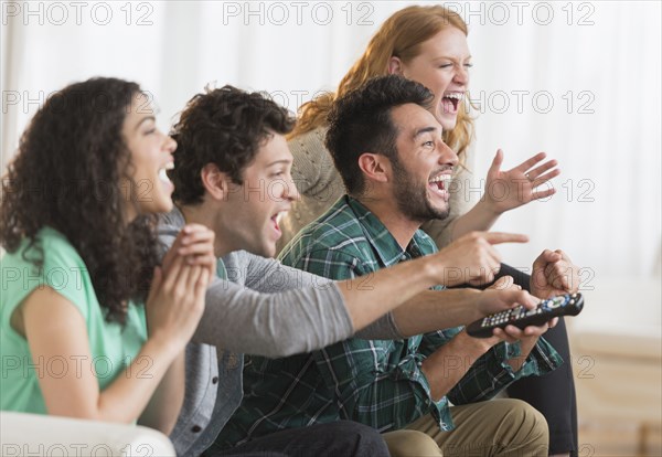 Friends watching television together on sofa