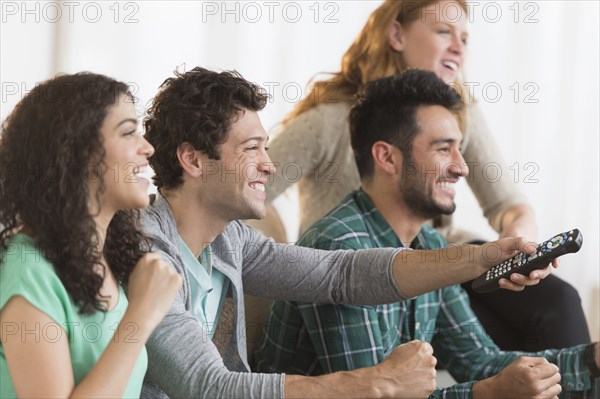 Friends watching television together on sofa