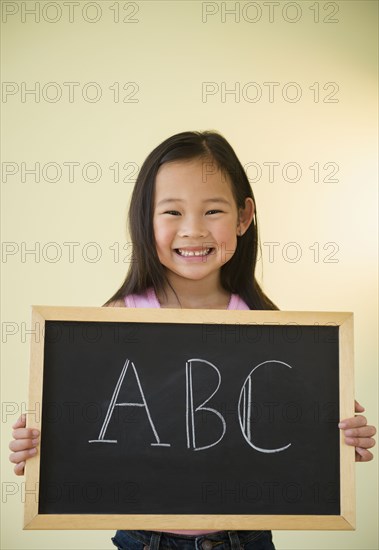 Korean girl holding chalkboard with ABC text