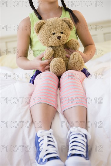 Korean girl holding teddy bear on bed